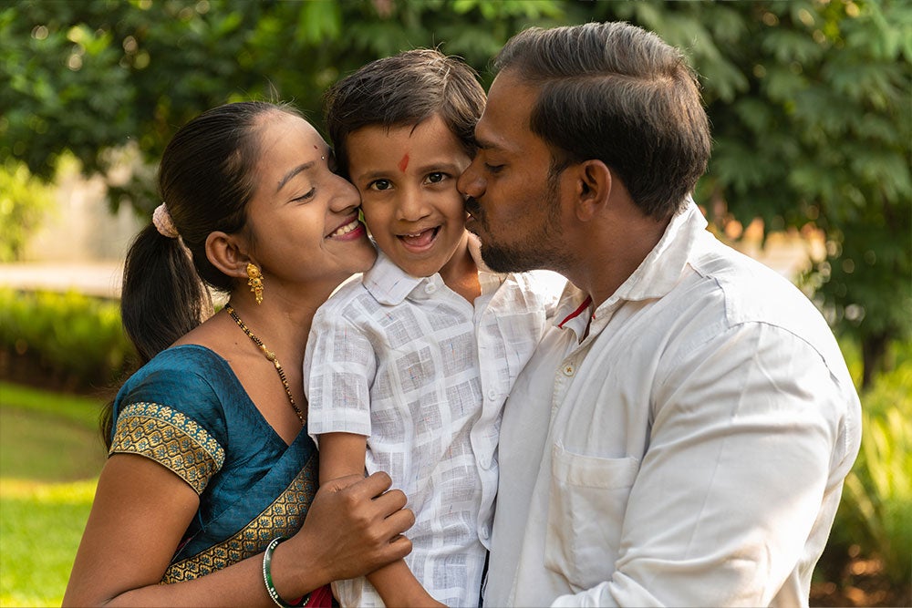 Manthan recevant un bisou sur chaque joue de la part de ses parents.