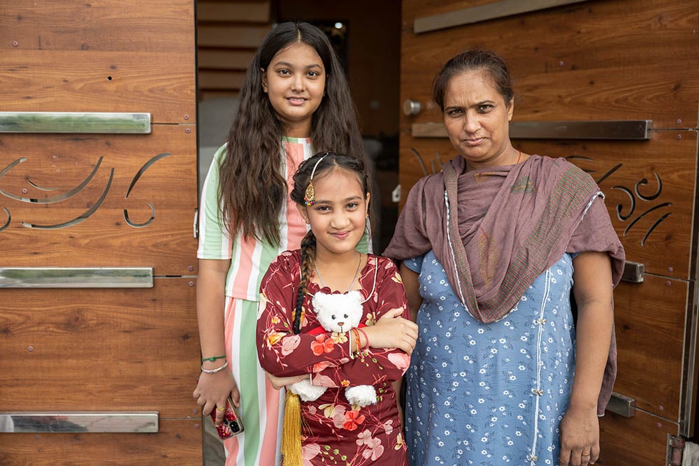 Bhumika souriant en tenant un ours en peluche Smile Train avec sa sœur et sa mère Jyoti après sa chirurgie de la fente