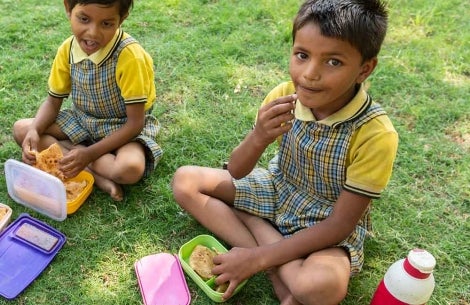 Two kids sitting down and eating lunch