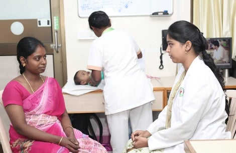 Un médecin discute avec une mère pendant que son enfant avec une fente est examiné par un autre médecin
