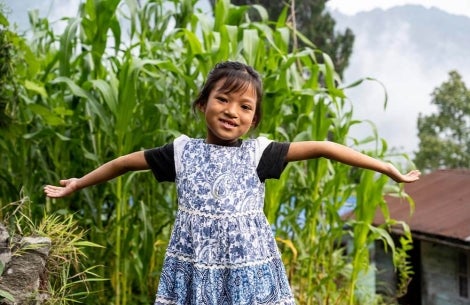 Smile Train patient smiling with her arms open after cleft surgery