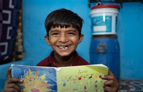 Smile Train patient smiling and holding a book after cleft surgery
