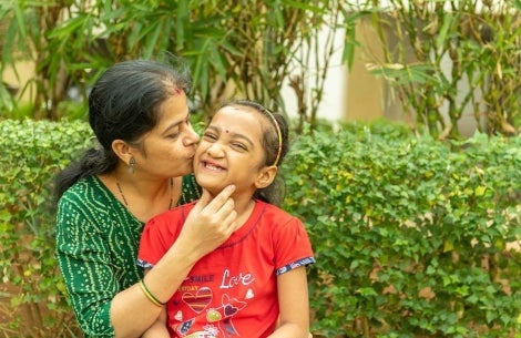 Smile Train patient smiling and kissing her mother after cleft surgery