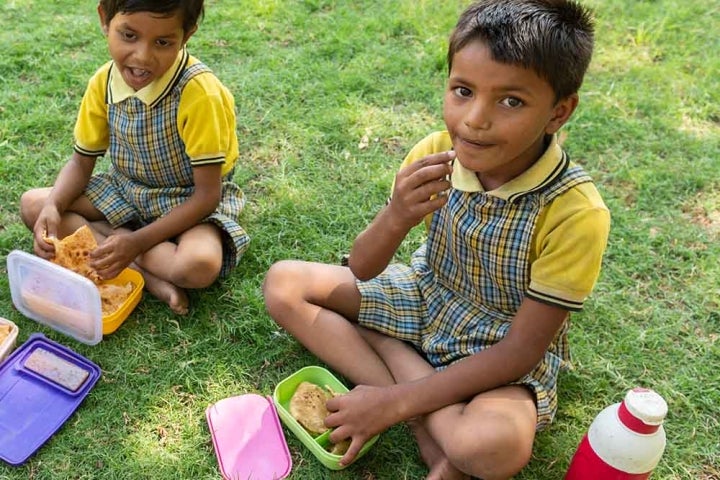 Two kids sitting down and eating lunch