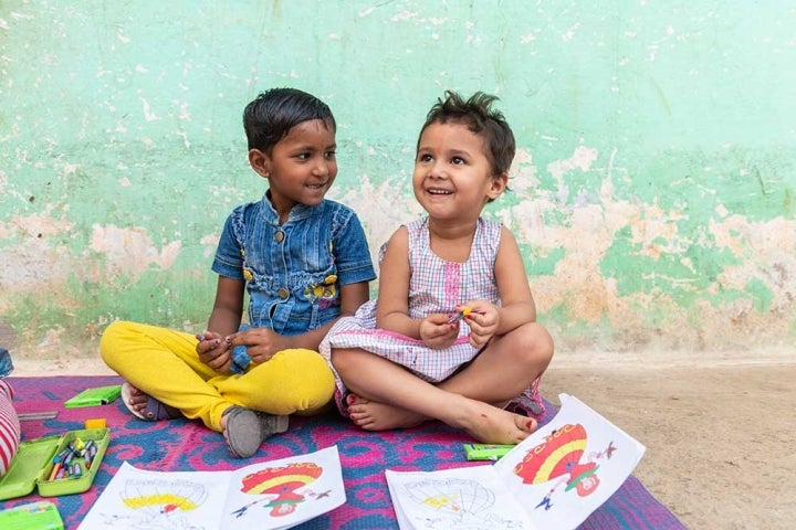 Des enfants souriant et coloriant dans un livre