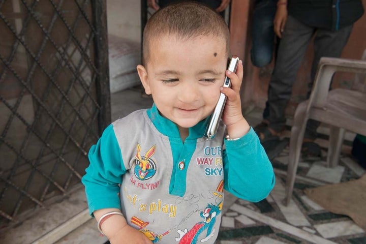 Un garçon tient son téléphone contre son oreille comme s'il passait un appel téléphonique