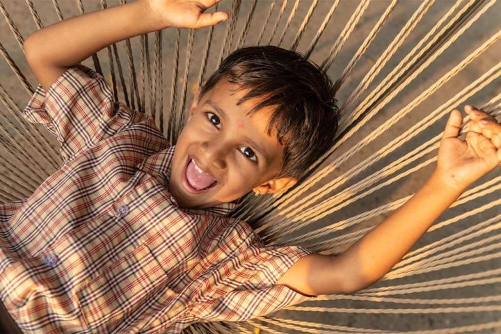 Smile Train patient Manthan smiling and laying in a hammock after cleft surgery