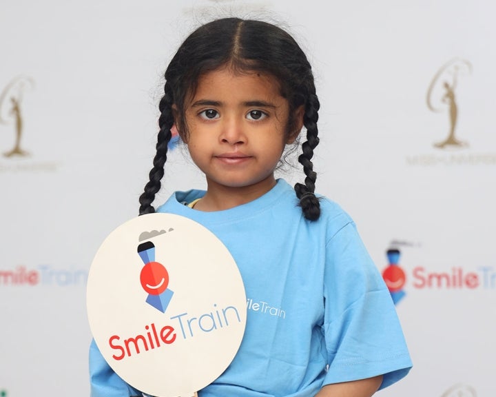 Une fille tient une affiche de Smile Train