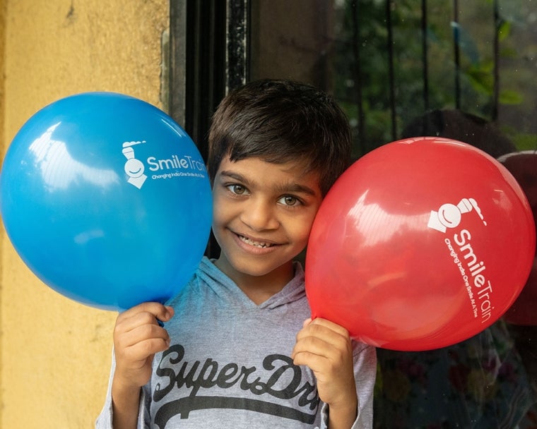 Samrat souriant et tenant des ballons Smile Train après sa chirurgie de la fente